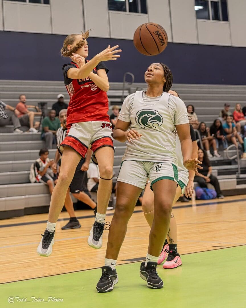 Two female basketball players compete intensely during a game.